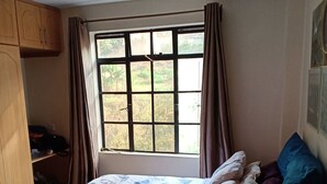 Une chambre à coucher avec un lit, une fenêtre, une armoire et une petite table.