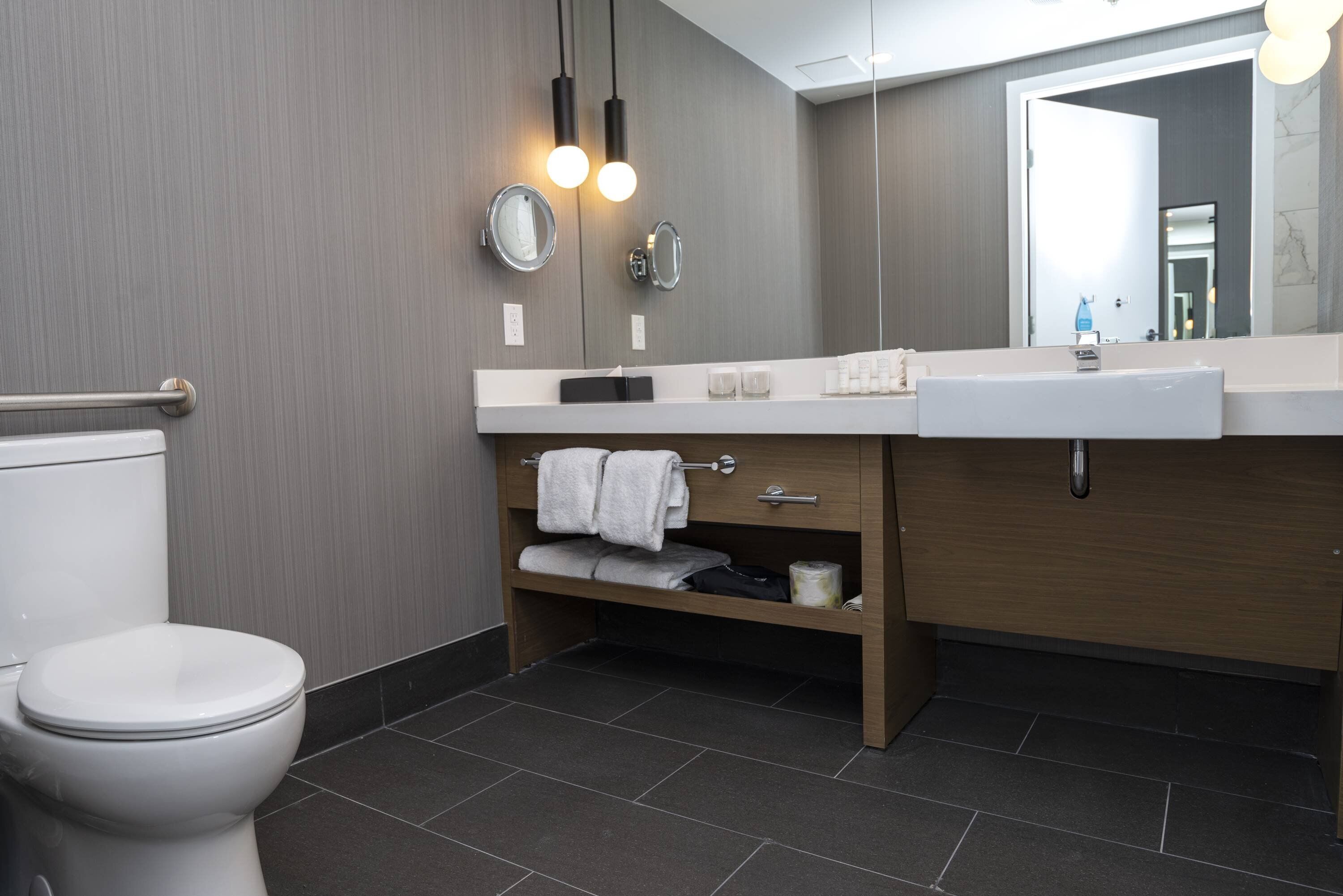 Een moderne badkamer met toilet, wastafel en spiegel.