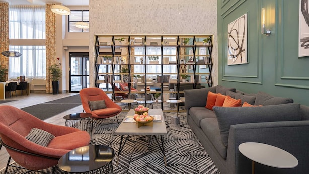 Een moderne lobby met een centraal zitgedeelte, een boekenkast en een groene accentmuur.