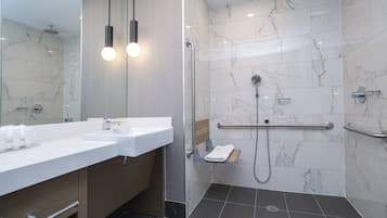 A modern bathroom with a dual sink vanity, a walk-in shower with a handheld showerhead, and a grab bar for safety.