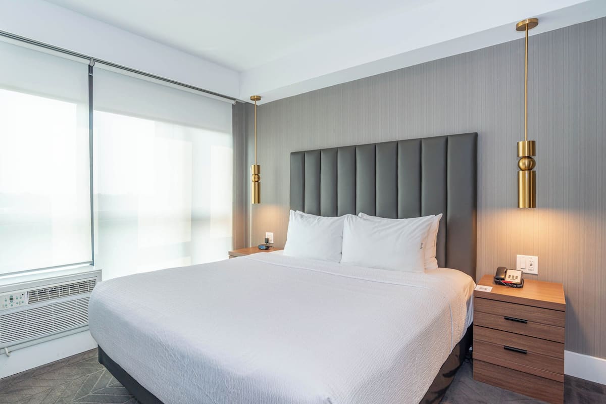 Een moderne hotelkamer met een groot bed, nachtkastje en een telefoon aan de muur.