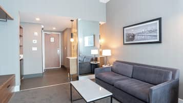 Een moderne hotelkamer met een grijze bank, een klein tafeltje, een spiegel en een inlijsting foto aan de muur.