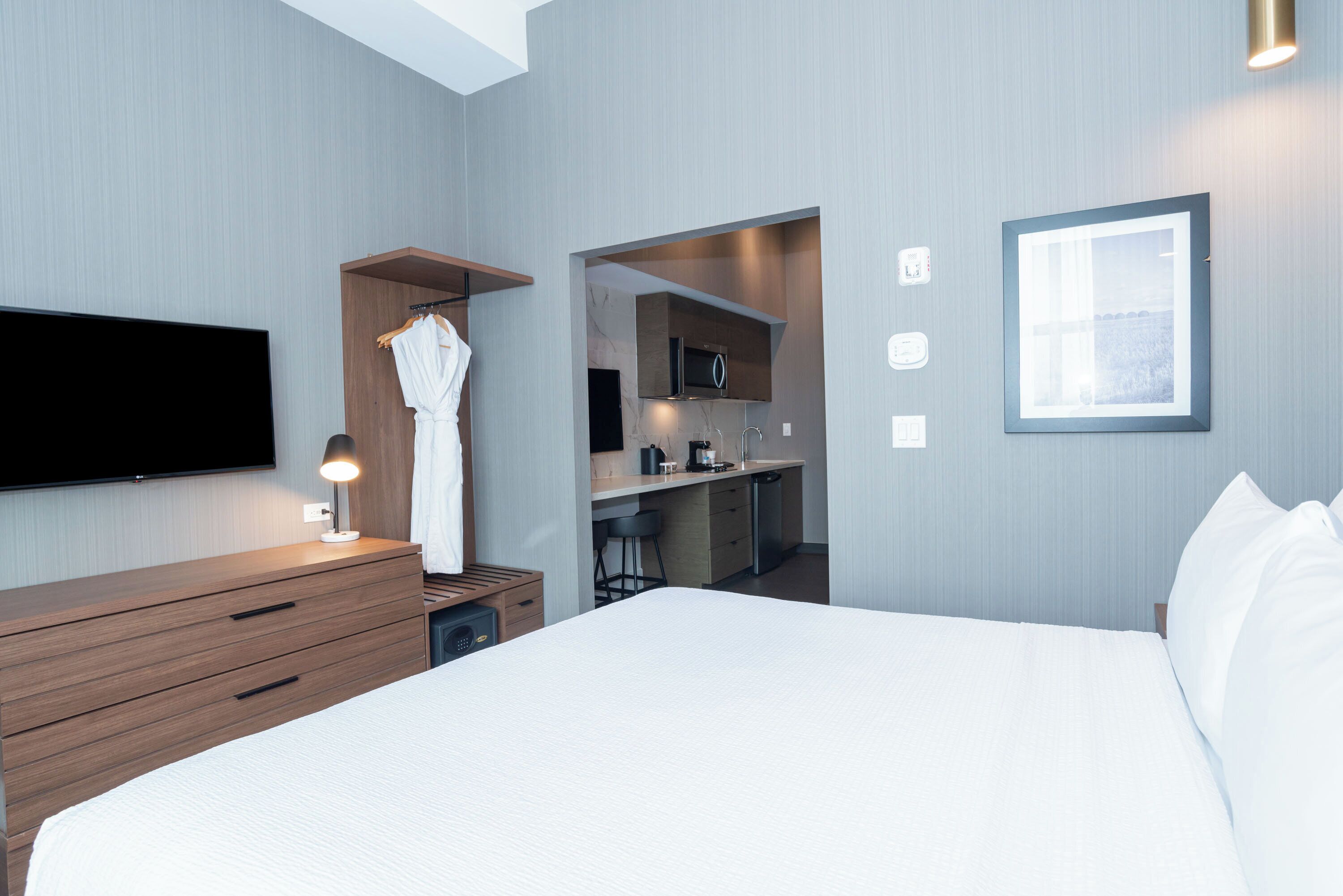 Een hotelkamer met een bed, een televisie, een bureau, een magnetron en een kleine kitchenette.