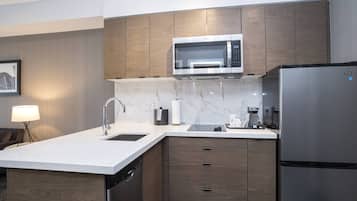 A modern kitchen with a built-in microwave, stainless steel refrigerator, and wooden cabinets.