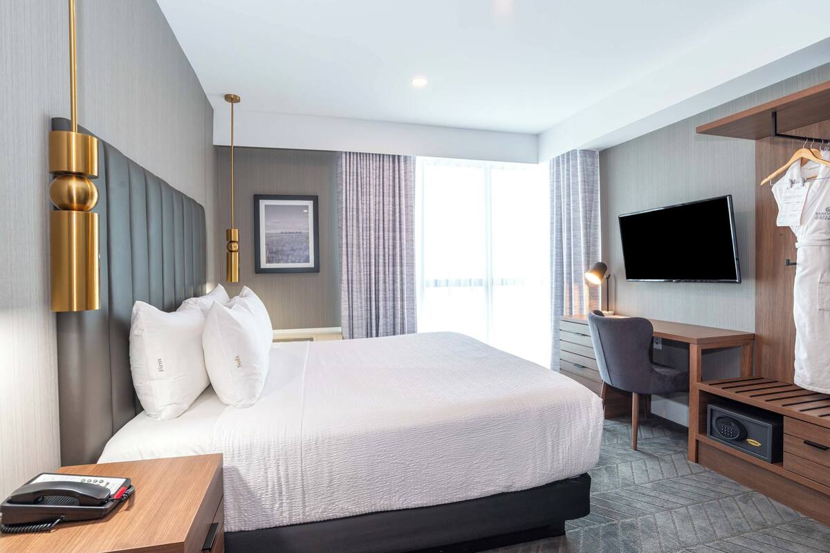 Een hotelkamer met een groot bed, een bureau, een stoel, een televisie en een kledingkast.