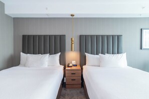 Een hotelkamer met twee bedden, een nachtkastje met lamp en een neutraal kleurenschema.
