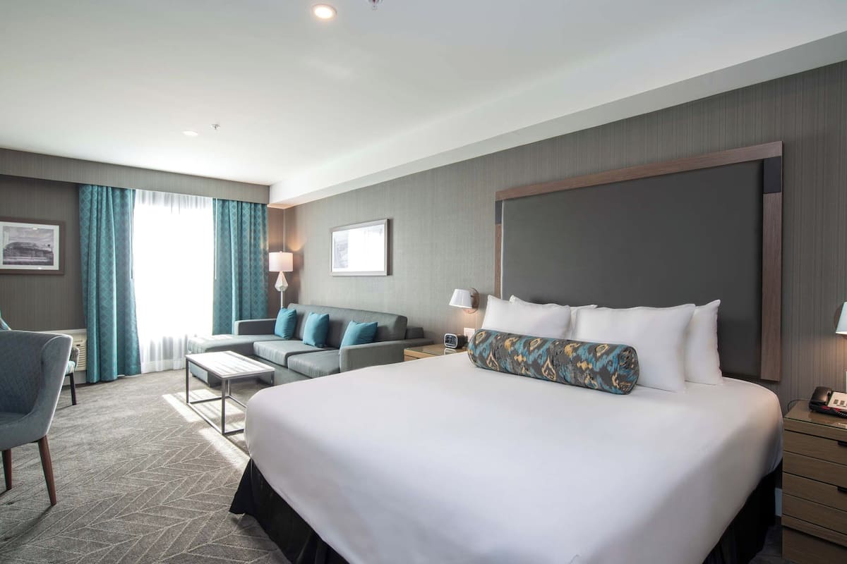 Ein Hotelzimmer mit einem großen Bett, einer Couch, einem Schreibtisch und einem Sessel.