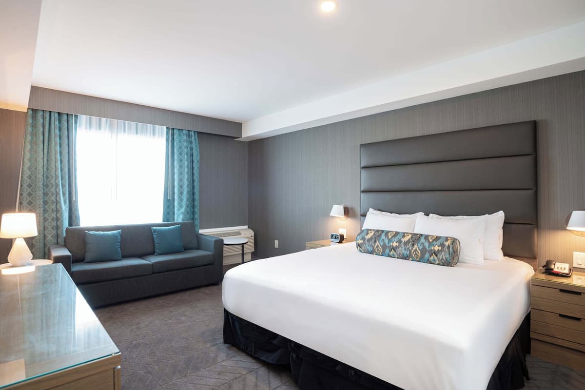 Ein Hotelzimmer mit einem großen Bett, einem Schlafsofa, einem Schreibtisch und einem Nachttisch.