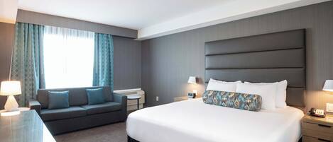 Una habitación de hotel con una cama grande, un sofá, un escritorio y una mesita de noche.