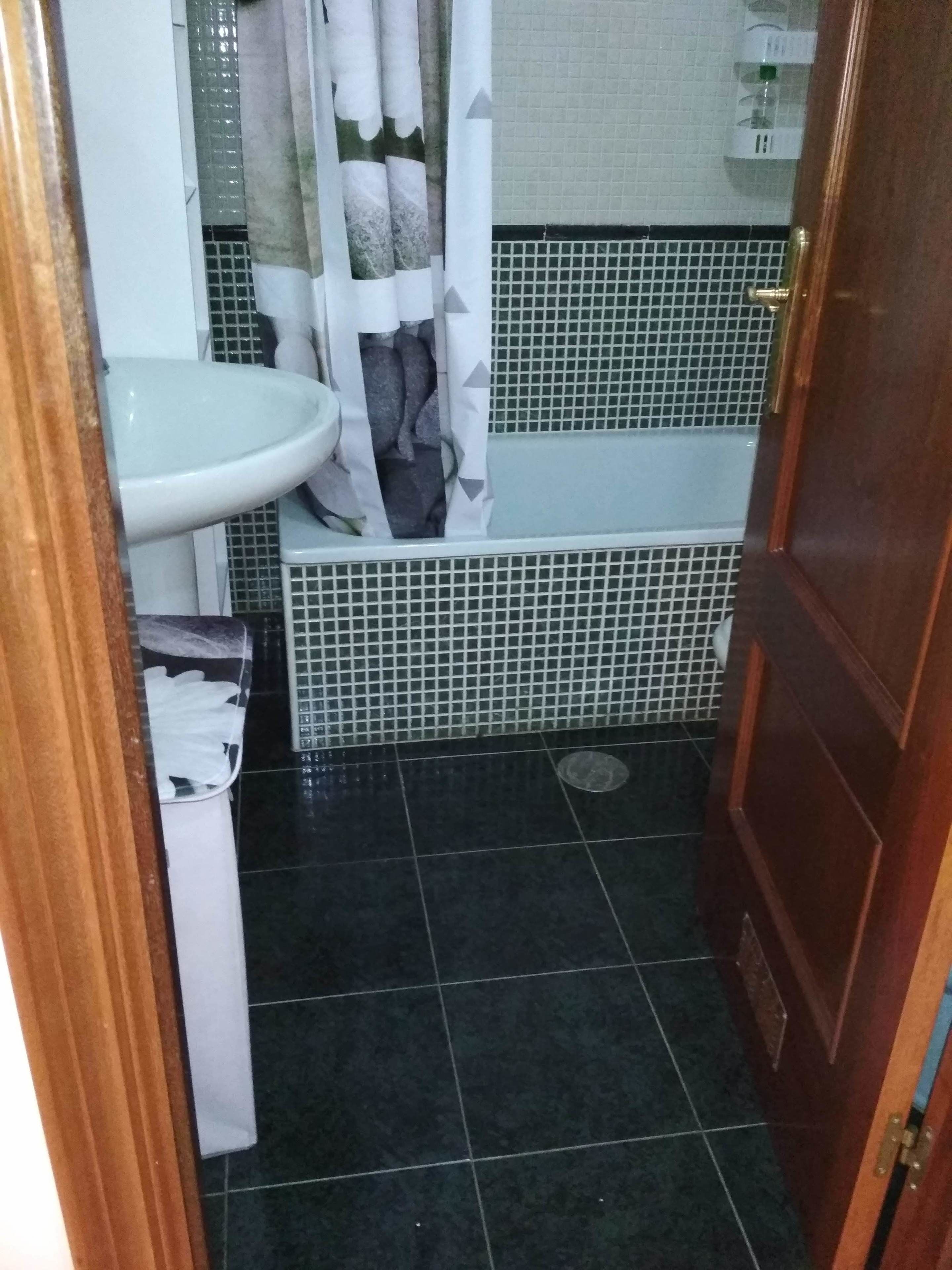 Un baño con un lavamanos blanco, una bañera con detalles de azulejos y una zona de ducha.