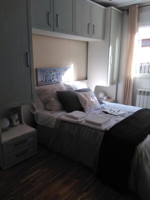 Een slaapkamer met een bed, nachtkastje en een kledingkast.