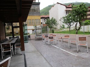 Een terras buiten met zitplaatsen en uitzicht op de omliggende gebouwen.