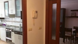 Een keuken met witte kasten, een inbouwoven en een telefoon aan de muur.