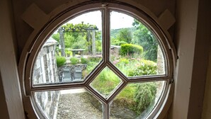 A circular window with a diamond pattern, overlooking a garden with a stone pathway and outdoor seating. - The School House, Coryton - a peaceful retreat  (sleeps 6+toddler) (Devon)