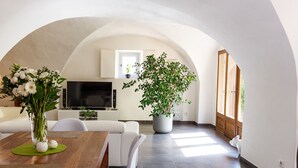 A modern living room with a dining area, a flat-screen TV, white furniture, and a large potted plant. - Loft "Reve d'Evan", design apartment - terrace & spa just for 2 (Carnas)