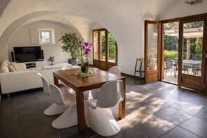 A modern interior with a dining table, white chairs, a sofa, a TV, and a potted plant. - Loft "Reve d'Evan", design apartment - terrace & spa just for 2 (Carnas)