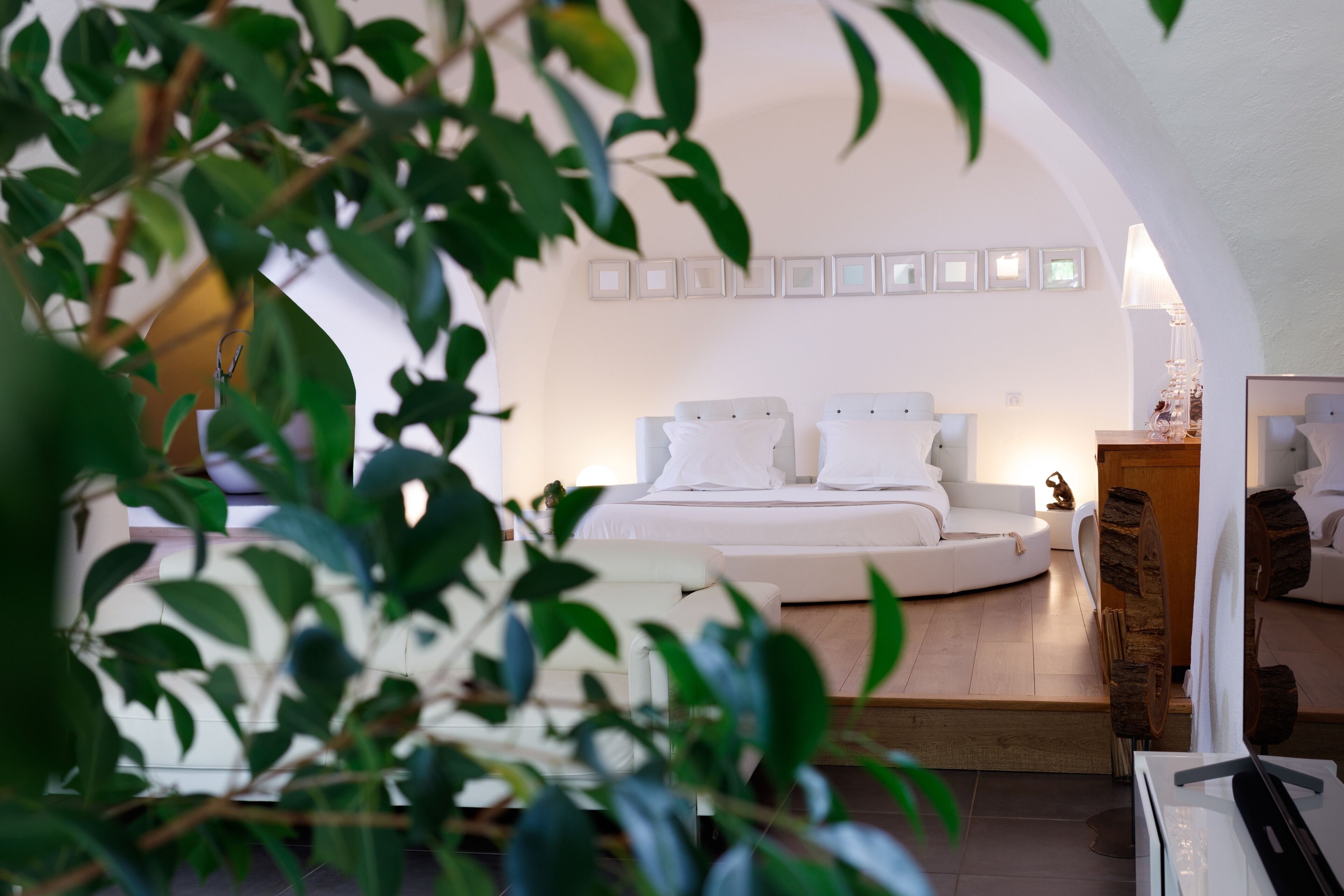 Une chambre à coucher moderne avec un lit aux lignes courbes, du linge de lit blanc et un design minimaliste.