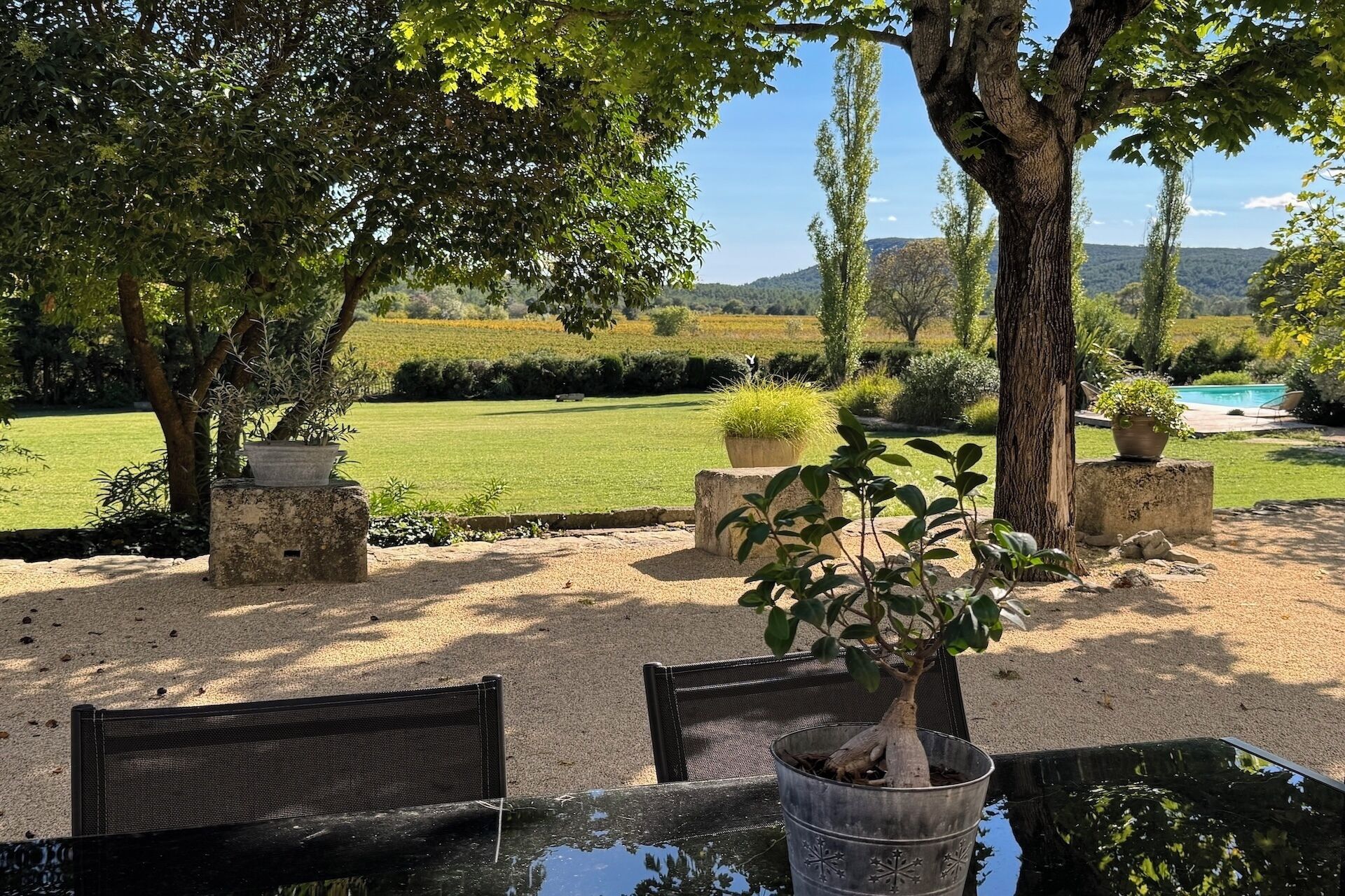 A garden with a pool, outdoor seating, and a view of the countryside.