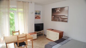 Un dormitorio con cama, televisión, escritorio y silla.