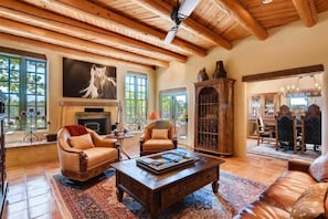 A spacious living room with a fireplace, leather sofas, and a large painting of a horse. - Los Valverde - Exclusive Luxury Home, Unsurpassed Views, Pool and Hot Tub! (Santa Fe)