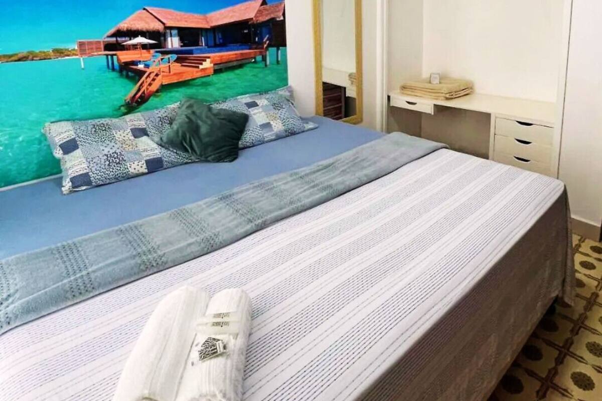 A neatly made bed with a striped bedspread and a rolled towel on the side.