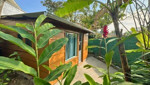 A small wooden structure with a window, surrounded by lush green foliage. - Tombo Beach (Guarujá)