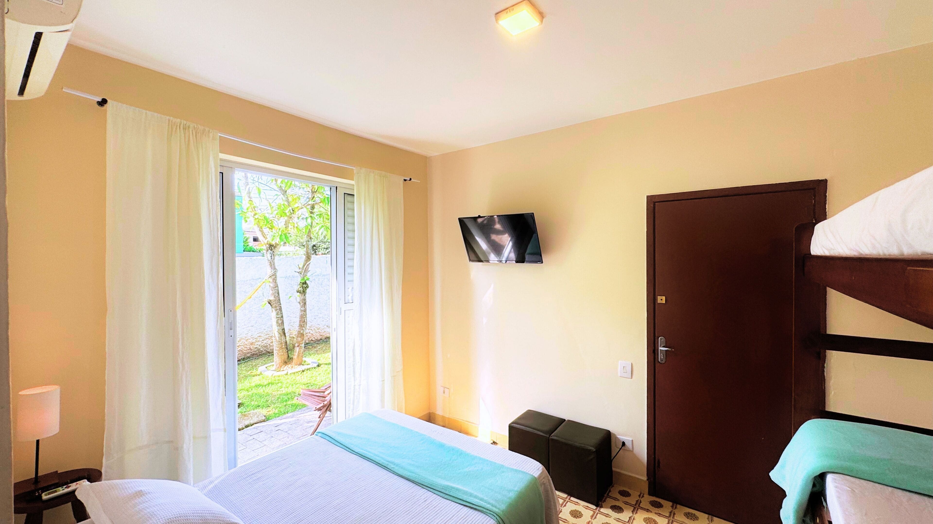 Une chambre d’hôtel avec un lit, une télévision, une porte et une fenêtre avec des rideaux.