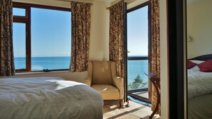 Een hotelkamer met een bed, een stoel en uitzicht op zee.