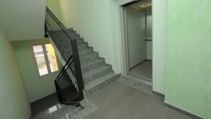 A staircase with a black railing leading to an elevator. - Comfortable Apartment in a Residence Code CIR 015209-CIM 00116 (Sesto San Giovanni)