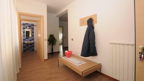 A hallway with a wooden floor, a small table with a red bowl, a coat hanging on a hook, and a radiator on the wall. - Comfortable Apartment in a Residence Code CIR 015209-CIM 00116 (Sesto San Giovanni)