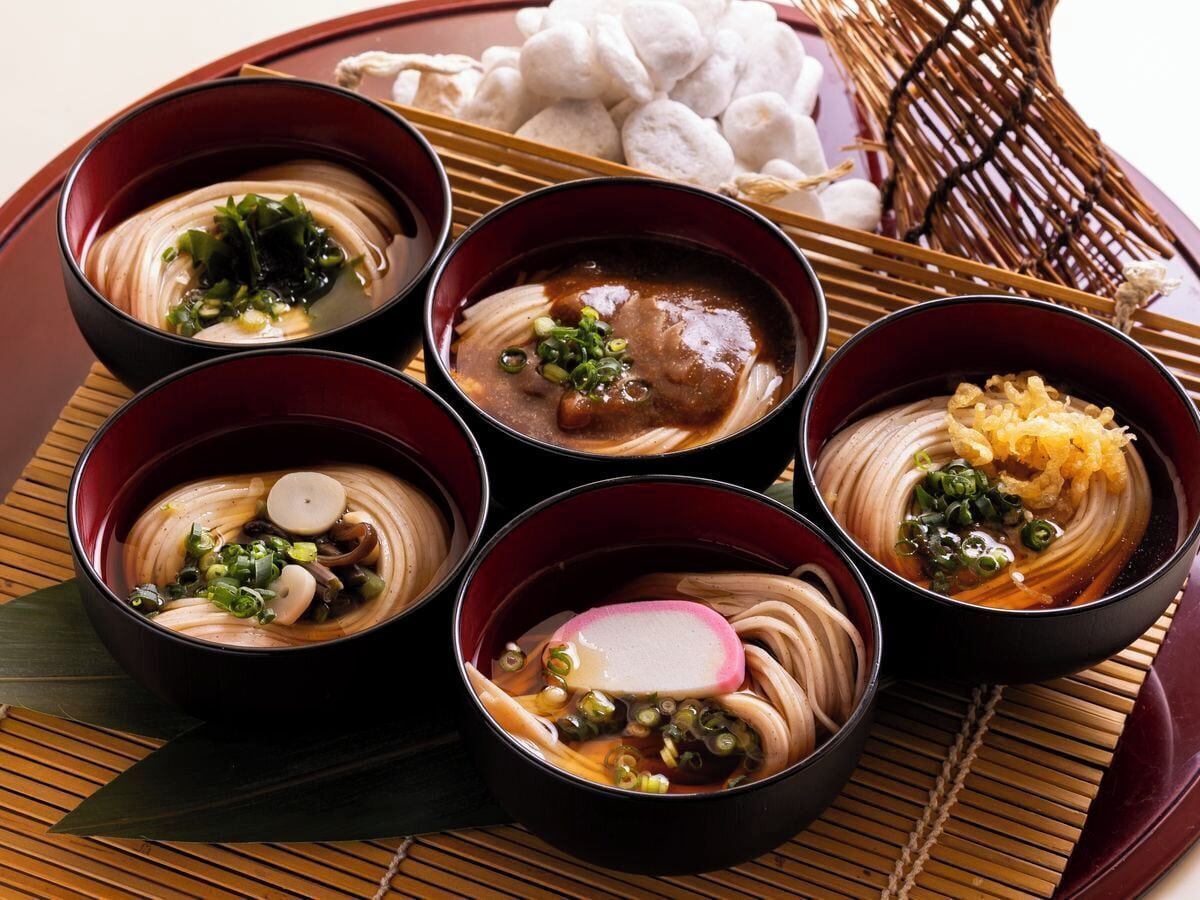 Six bowls of ramen with various toppings on a wooden tray.
