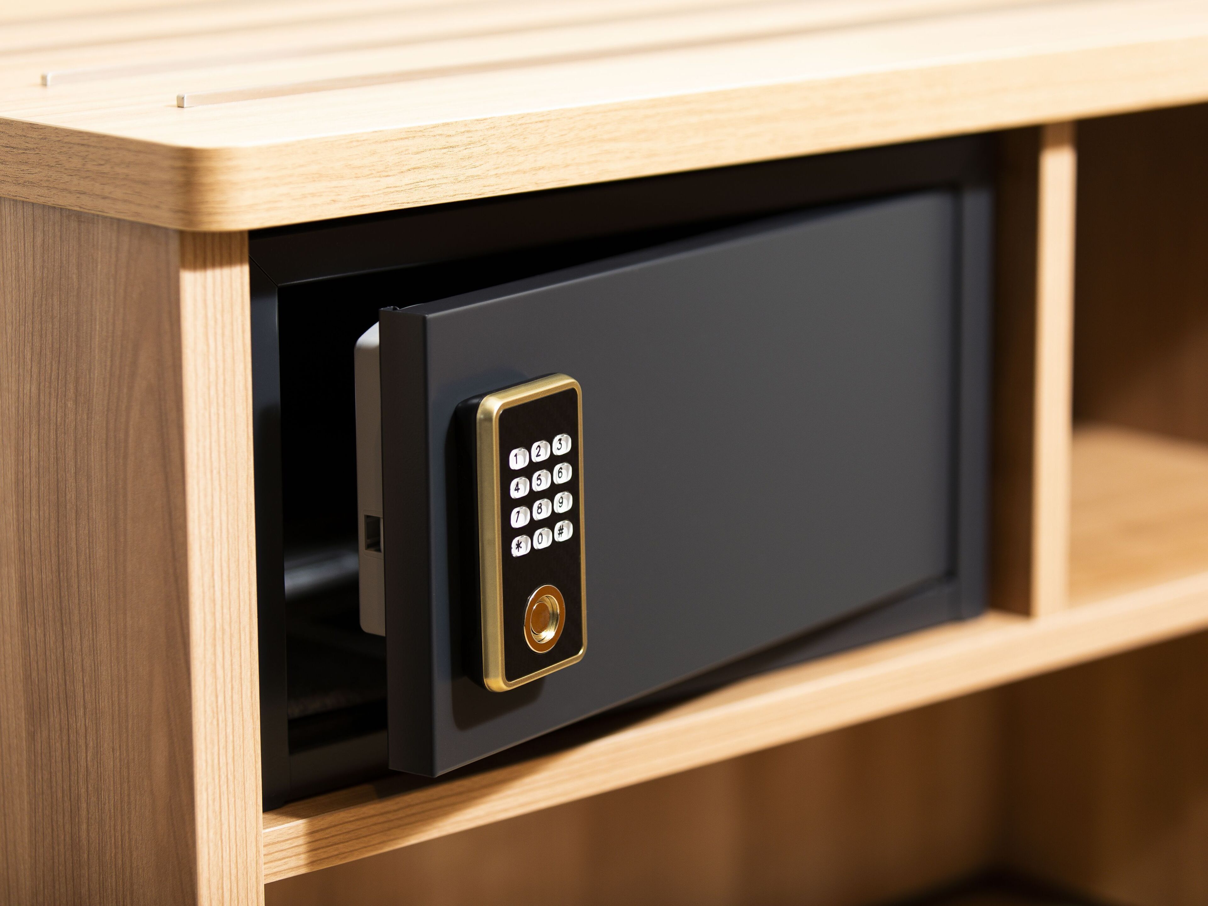 A secure, modern safe with a keypad lock, built into a wooden cabinet.