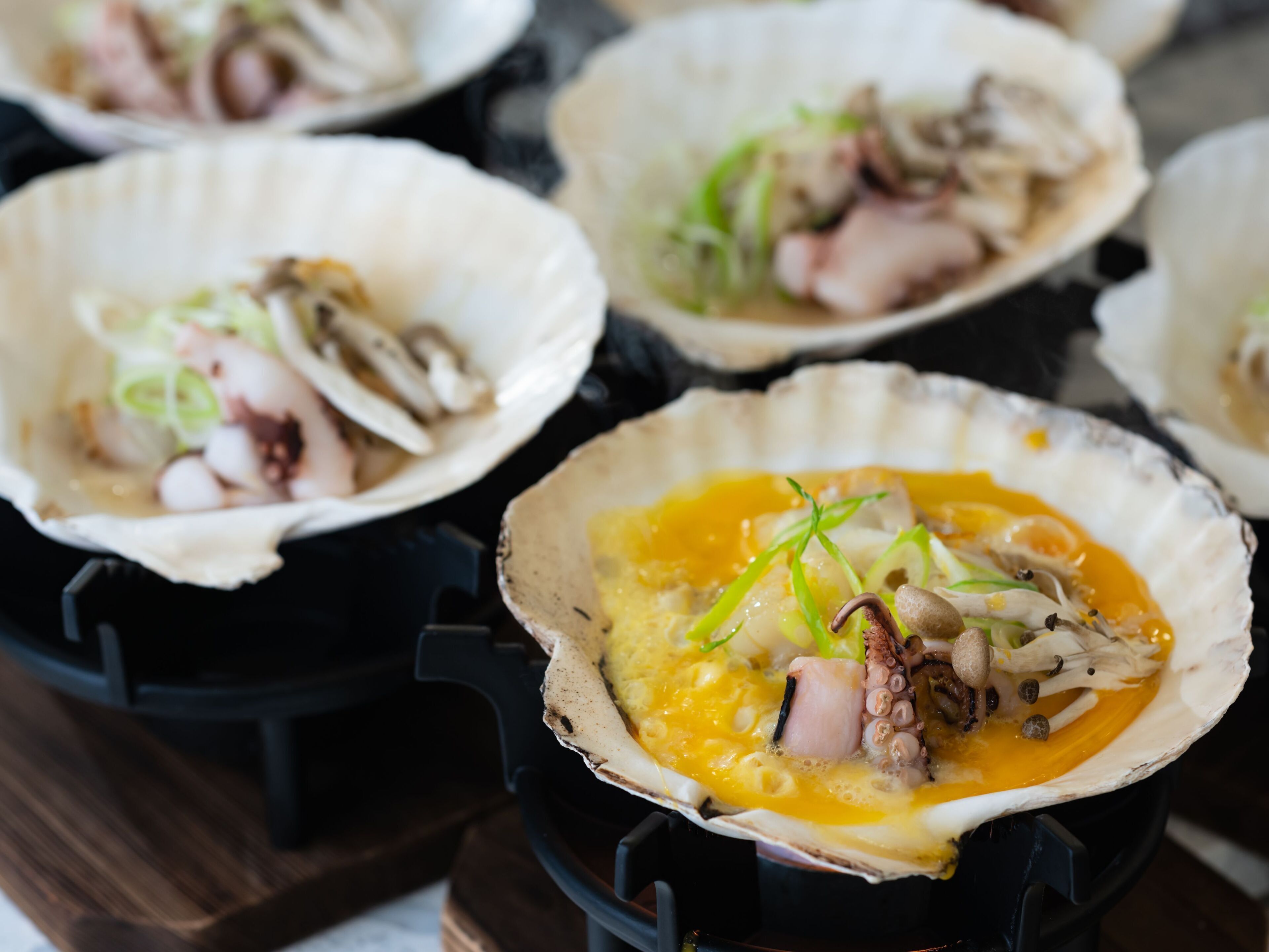 A close-up of a dish with octopus and mushrooms in a shell.