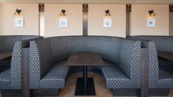 Un restaurante con una zona de estar curva, tapicería con estampado y una mesa central.