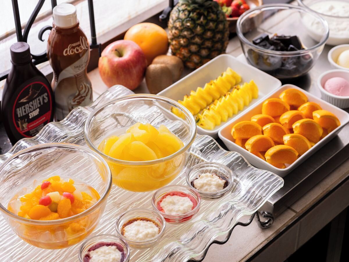 A breakfast buffet with various fruits, condiments, and a Hershey's syrup bottle.