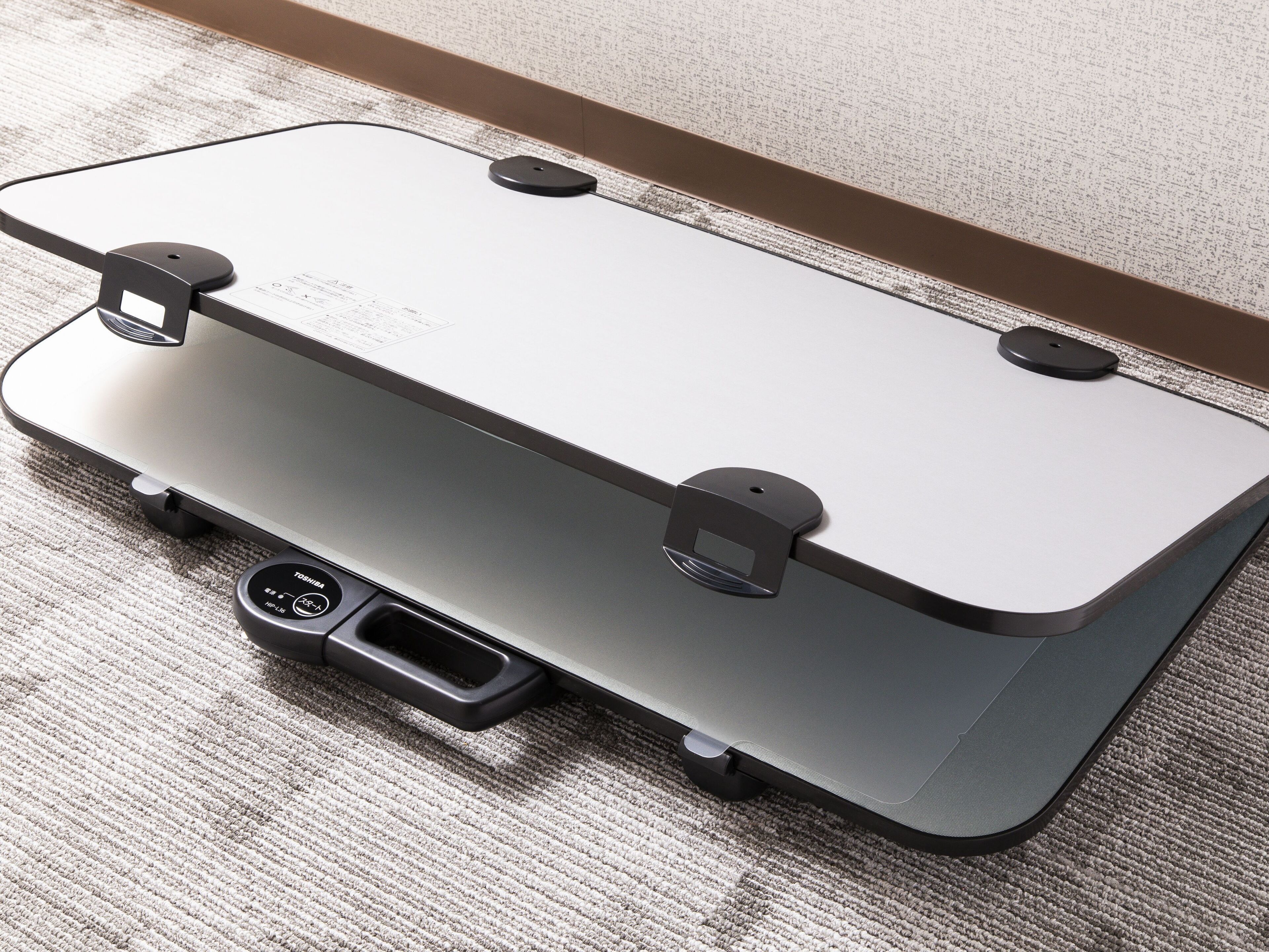 A suitcase with wheels and a handle, placed on a textured carpet.