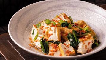 Tofu mit Gemüse und gebratenen Zwiebeln auf einem Teller.