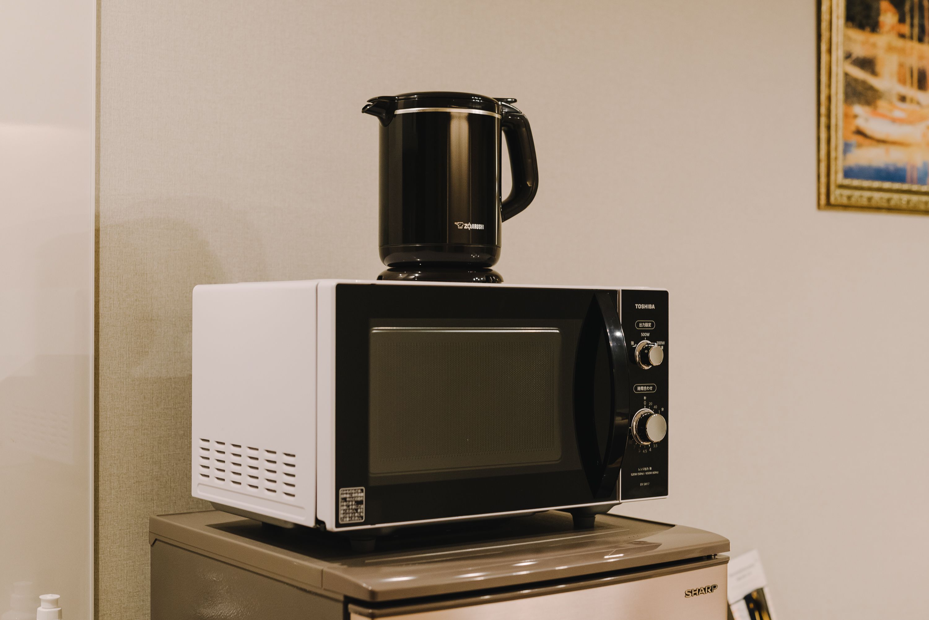 Eine Mikrowelle mit Kaffeemaschine darauf, auf einer Arbeitsplatte platziert.