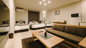 A hotel room with two beds, a sofa, a coffee table, a TV, and a microwave.
