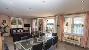 A modern dining area with a glass table and chairs, a sofa, and a television.