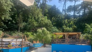 A pool area with a wooden deck, lounge chairs, and a covered seating area.