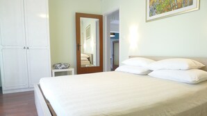 Une chambre à coucher avec un lit, une table de chevet, un miroir et une armoire.