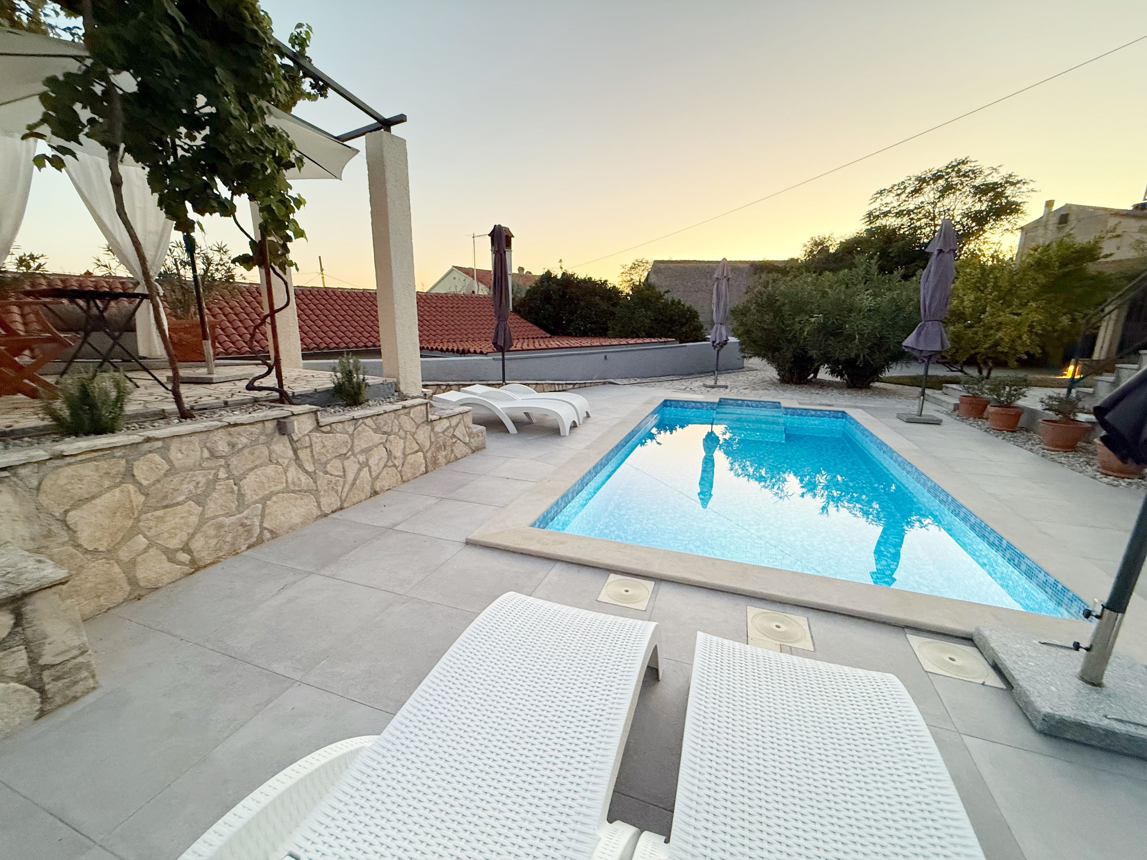 Una piscina con sillones de descanso y una pared de piedra.