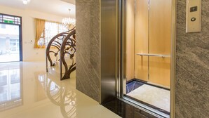 An elevator interior with a marble wall, a wooden door, and a control panel with directional arrows. - When Happiness Knock Your Door (Hualien City)