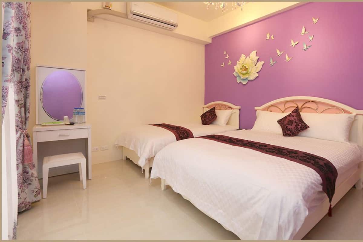 A bedroom with two beds, a small desk, a mirror, and a purple wall with butterfly decorations.