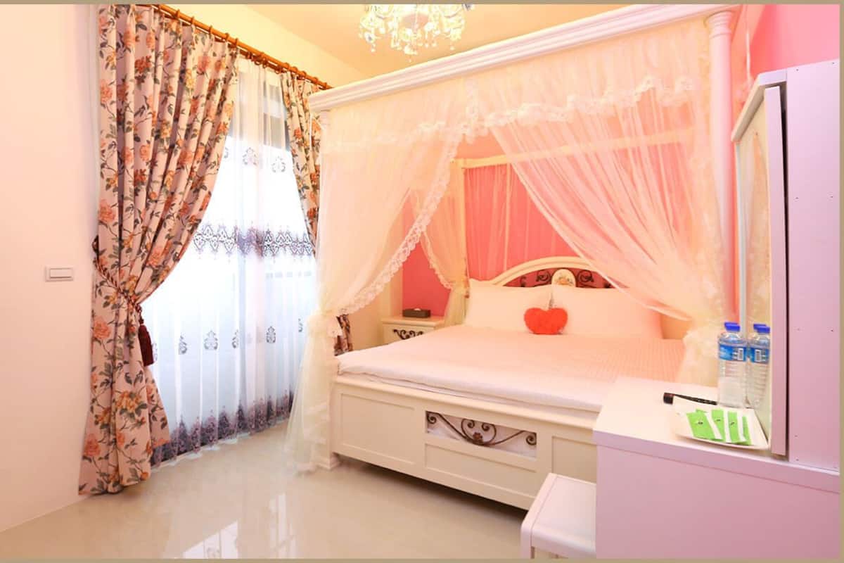 A bedroom with a bed, a nightstand, a bedside table, and a TV.
