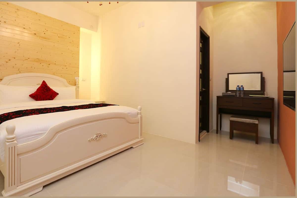 A bedroom with a bed, a dresser, and a mirror.