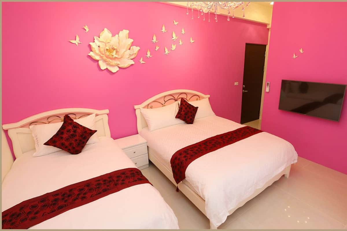 A room with two beds, a TV mounted on the wall, and a door.