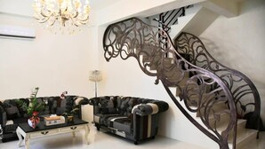A modern living room with a black and white sofa set, a white coffee table, and a decorative metal staircase railing. - When Happiness Knock Your Door (Hualien City)