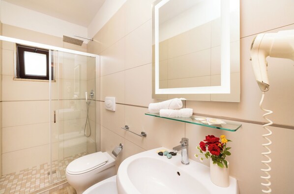 A modern bathroom with a glass shower enclosure, a white sink, and a vanity mirror.
